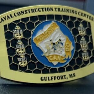 A belt buckle with the words " naval construction training center gulfport, ms ".