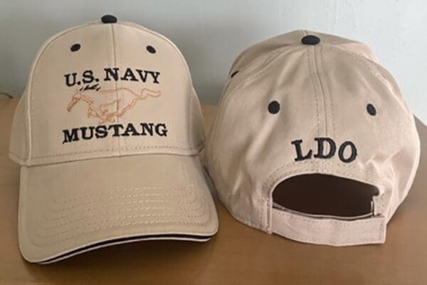 A pair of hats with the u. S. Navy mustang logo on one side and ldo on the other