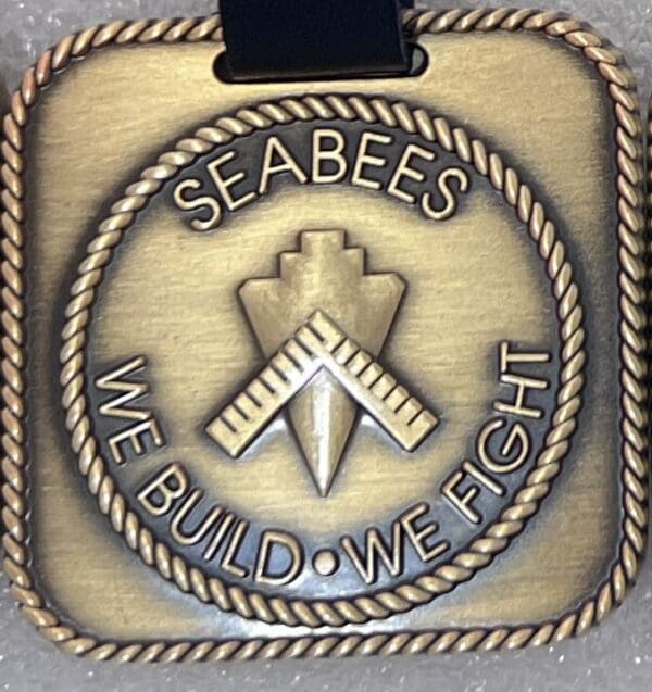 A medal with the words " seabees we build, we fight ".