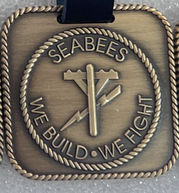 A medal with the words seabees we build, we fight.