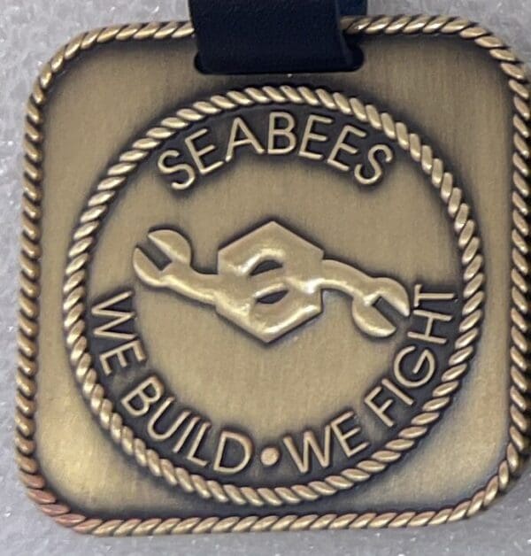 A medal with the words " seabees we build, we fight ".