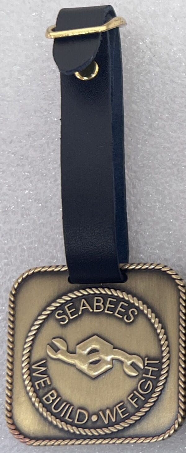 A gold and black tag with the name of seabees.