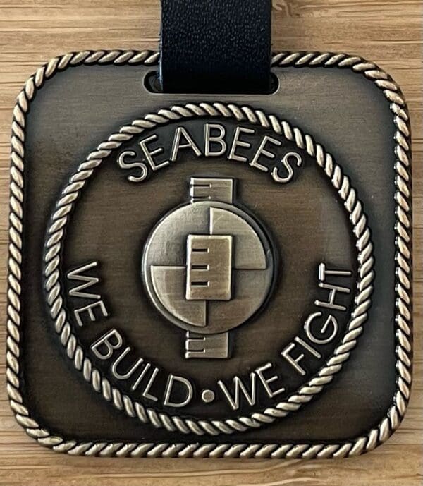 A medal with the words " seabees we build, we fight ".