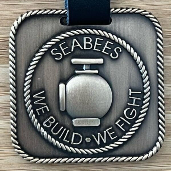 A medal with the words " seabees we build, we fight ".